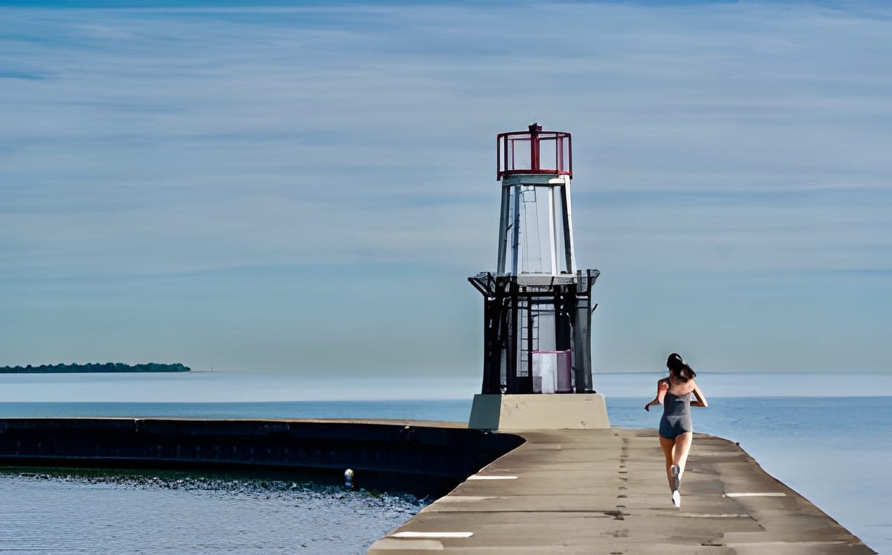 A runner approaching a beacon at the end of a pier on blue water