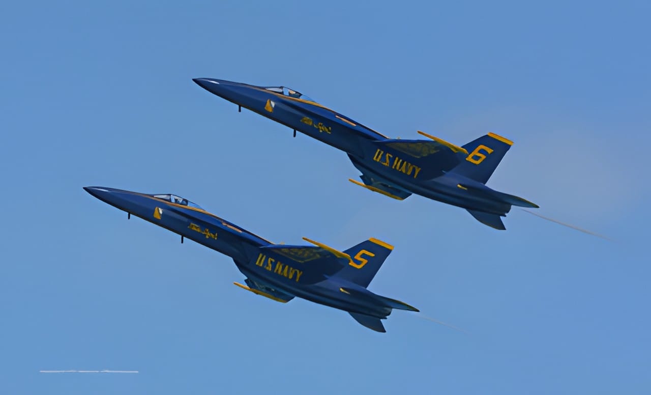 Two Blue Angels jets flying close together over the lake