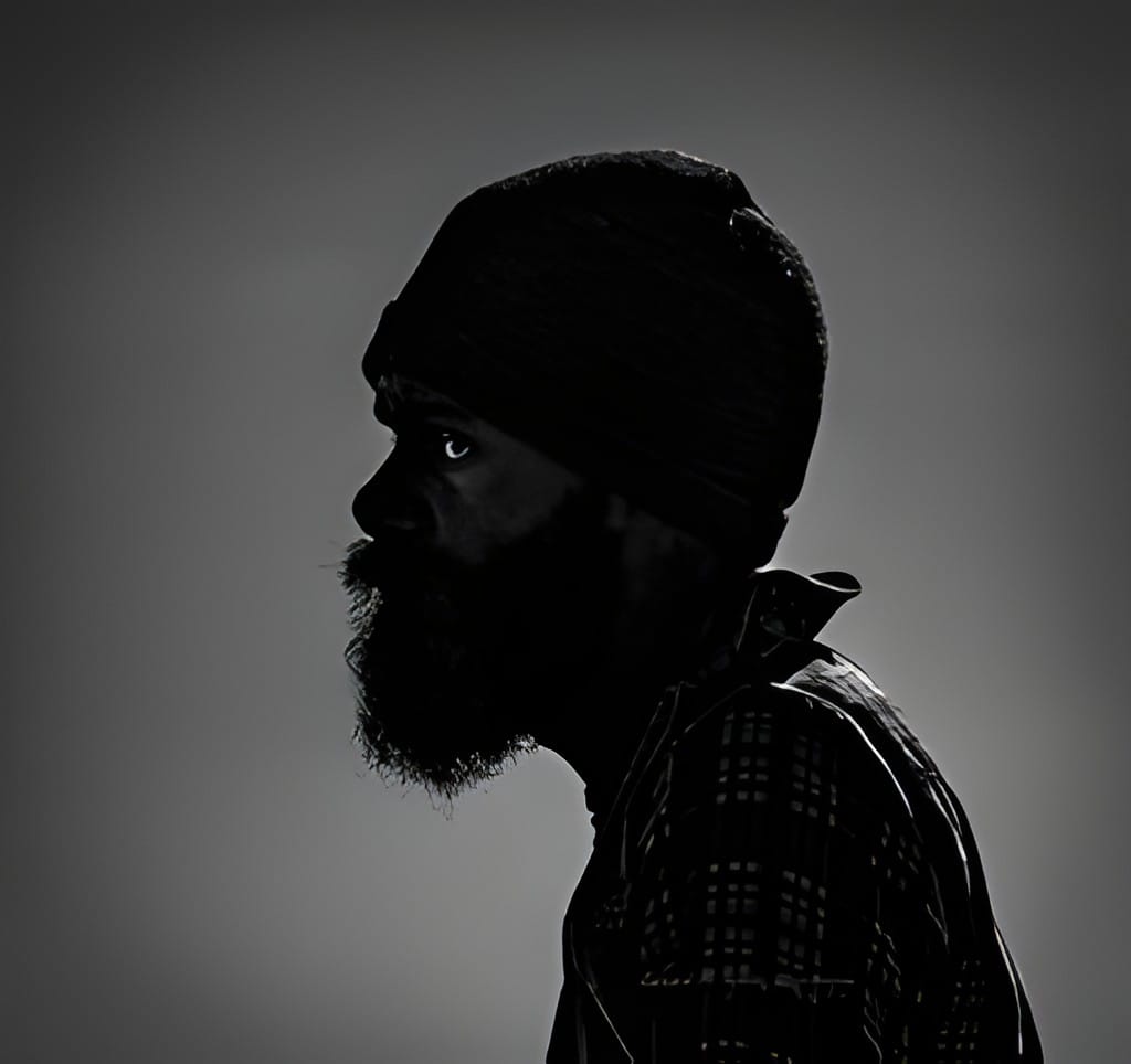 A black and white profile portrait of a bearded man