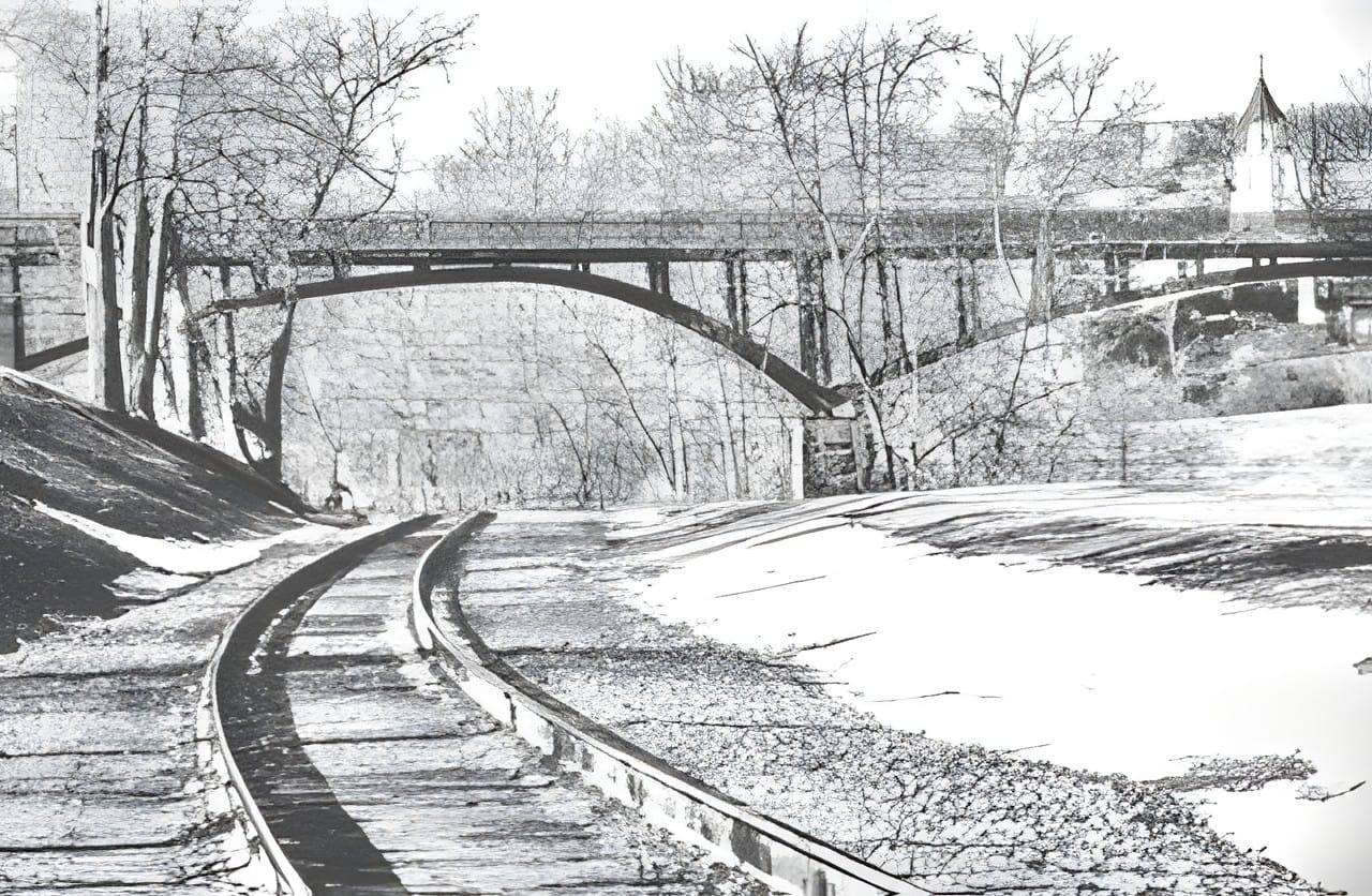 Railroad tracks curving away into snow, black and white