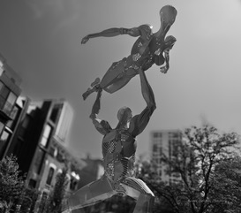 A bronze sculpture of two figures lifting, black and white