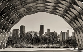 The Chicago skyline framed by the steel arches of Pritzker Pavilion, black and white