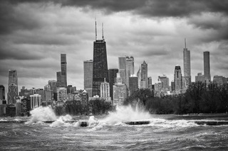 The Chicago skyline in black and white above a wave on the lake