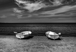 Two rowboats beached on a shore, black and white